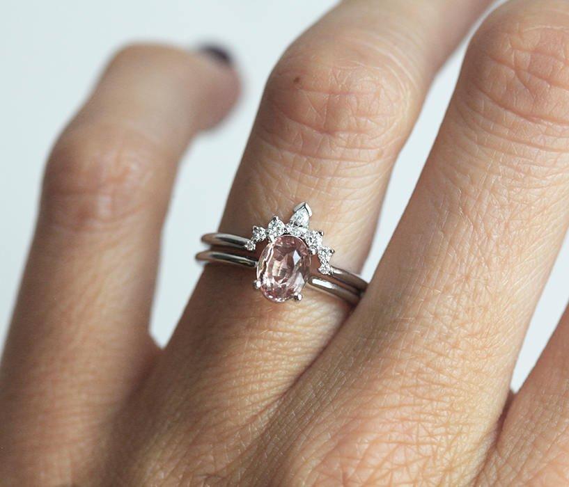 Oval peach pink sapphire engagement ring with diamond halo