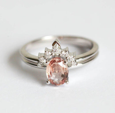 Oval peach pink sapphire engagement ring with diamond halo