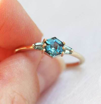 Hexagon-shaped teal sapphire ring with trapezoid side sapphires
