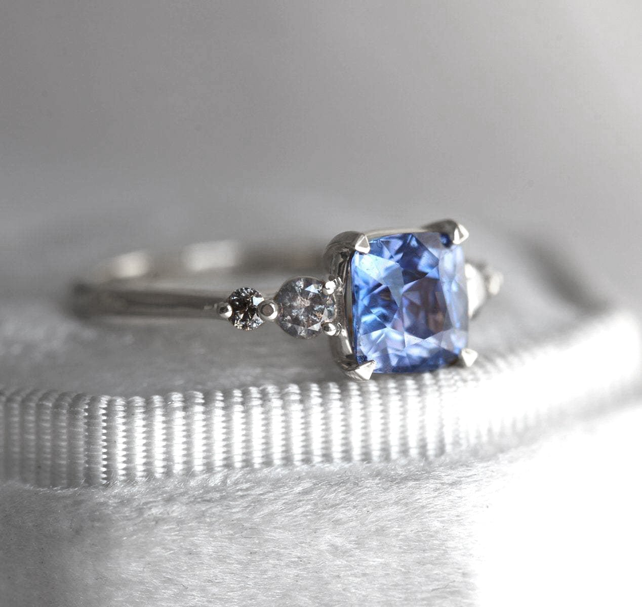 Cushion-cut blue sapphire cluster ring with round salt and pepper diamonds