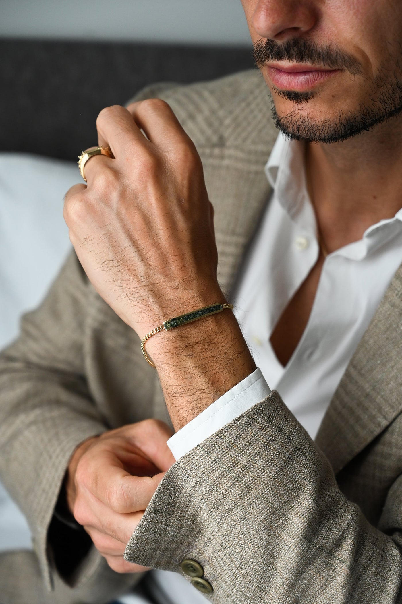 A man's hand wearing a gold signet ring with a snake spine design.