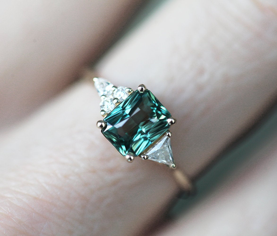 Radiant-cut teal sapphire cluster ring with diamonds