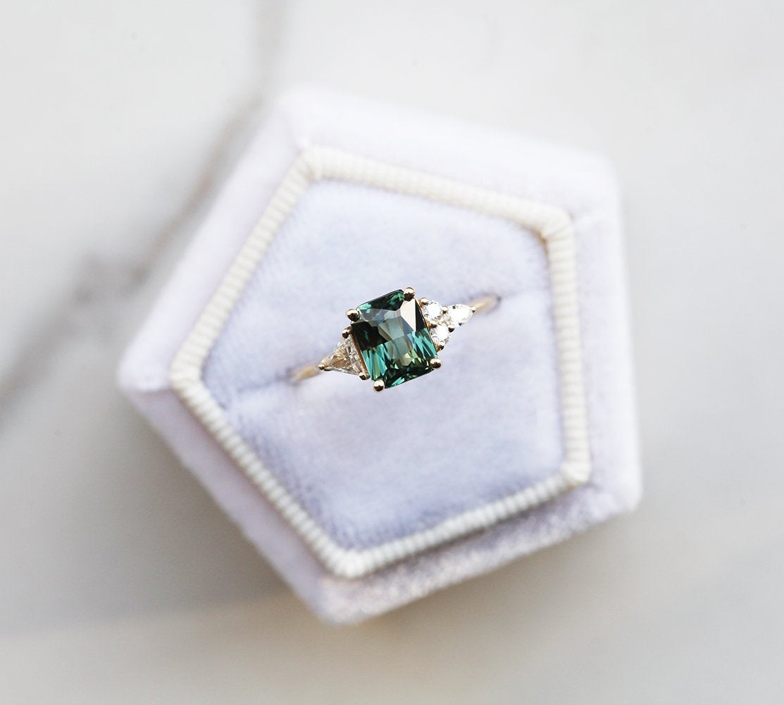 Radiant-cut teal sapphire cluster ring with diamonds