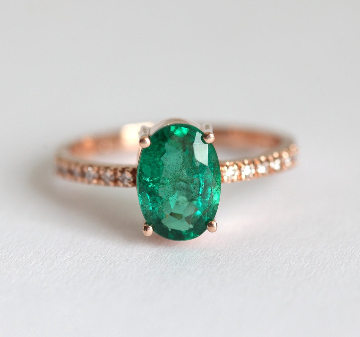 Close-up of Oval Emerald Ring with oval green emerald and pave band.