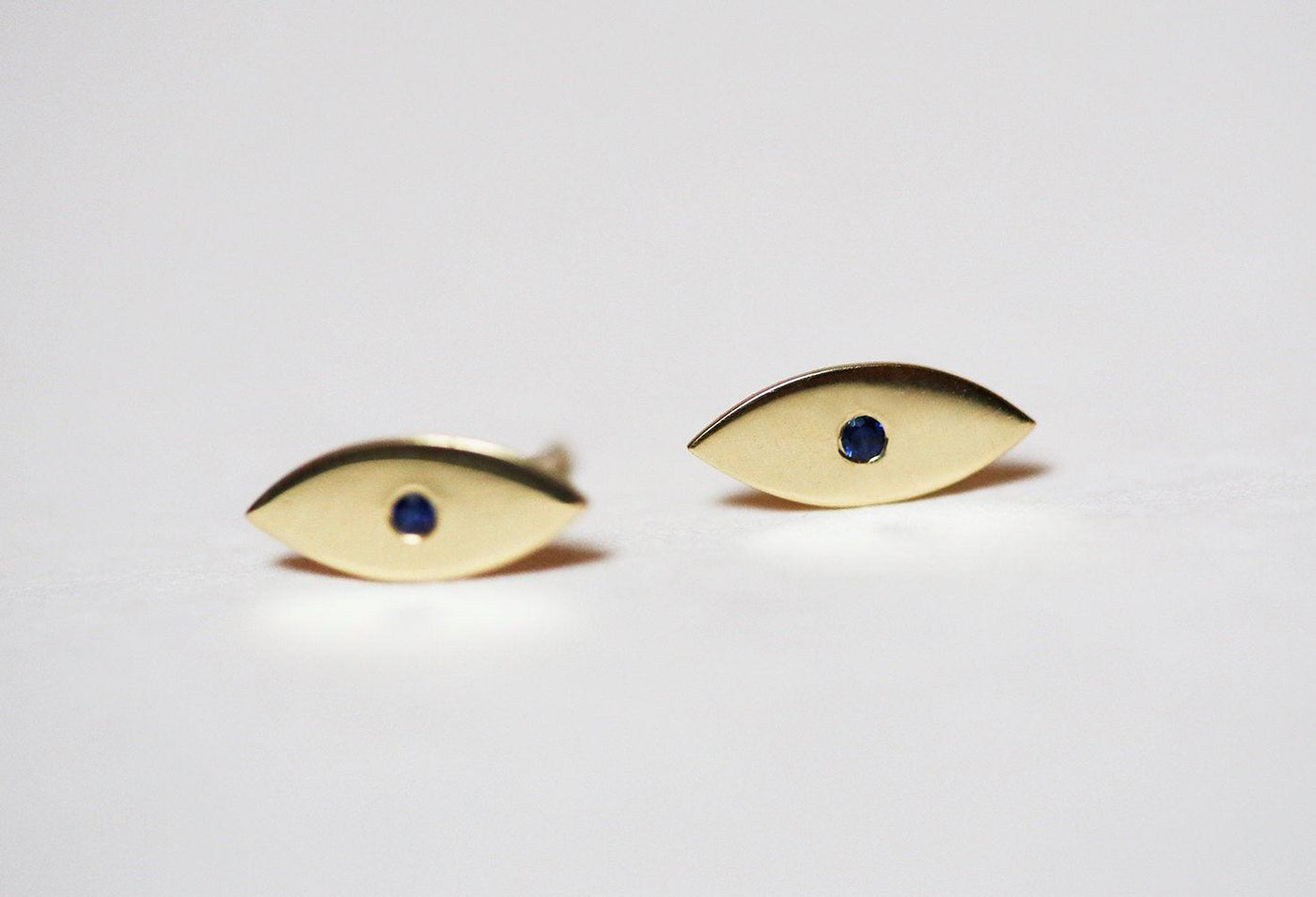 Evil-eye-shaped stud earrings with round blue sapphires