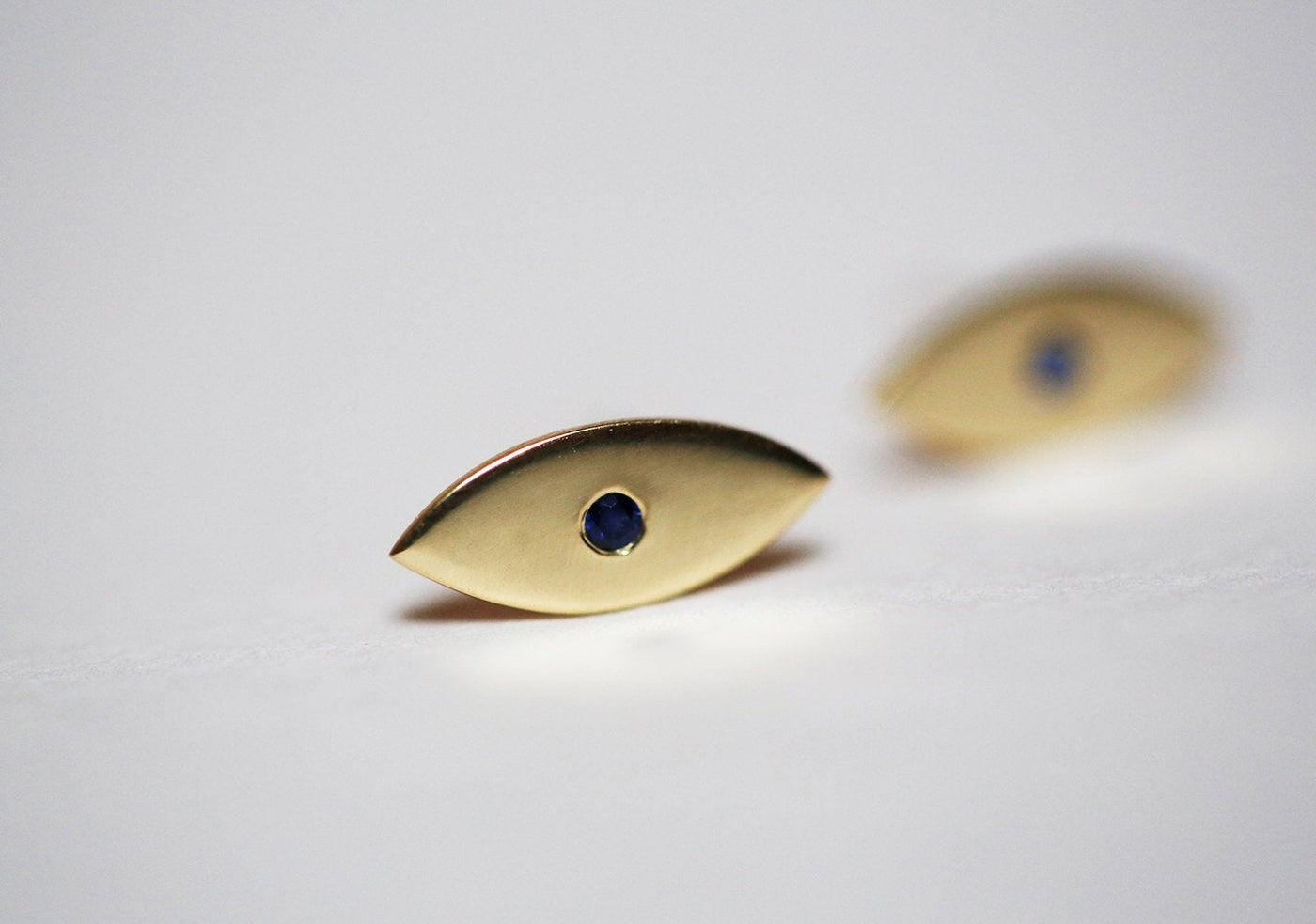 Evil-eye-shaped stud earrings with round blue sapphires