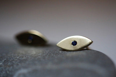 Evil-eye-shaped stud earrings with round blue sapphires