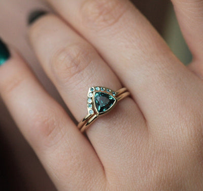 Trillion-cut teal sapphire engagement ring with blue diamond band