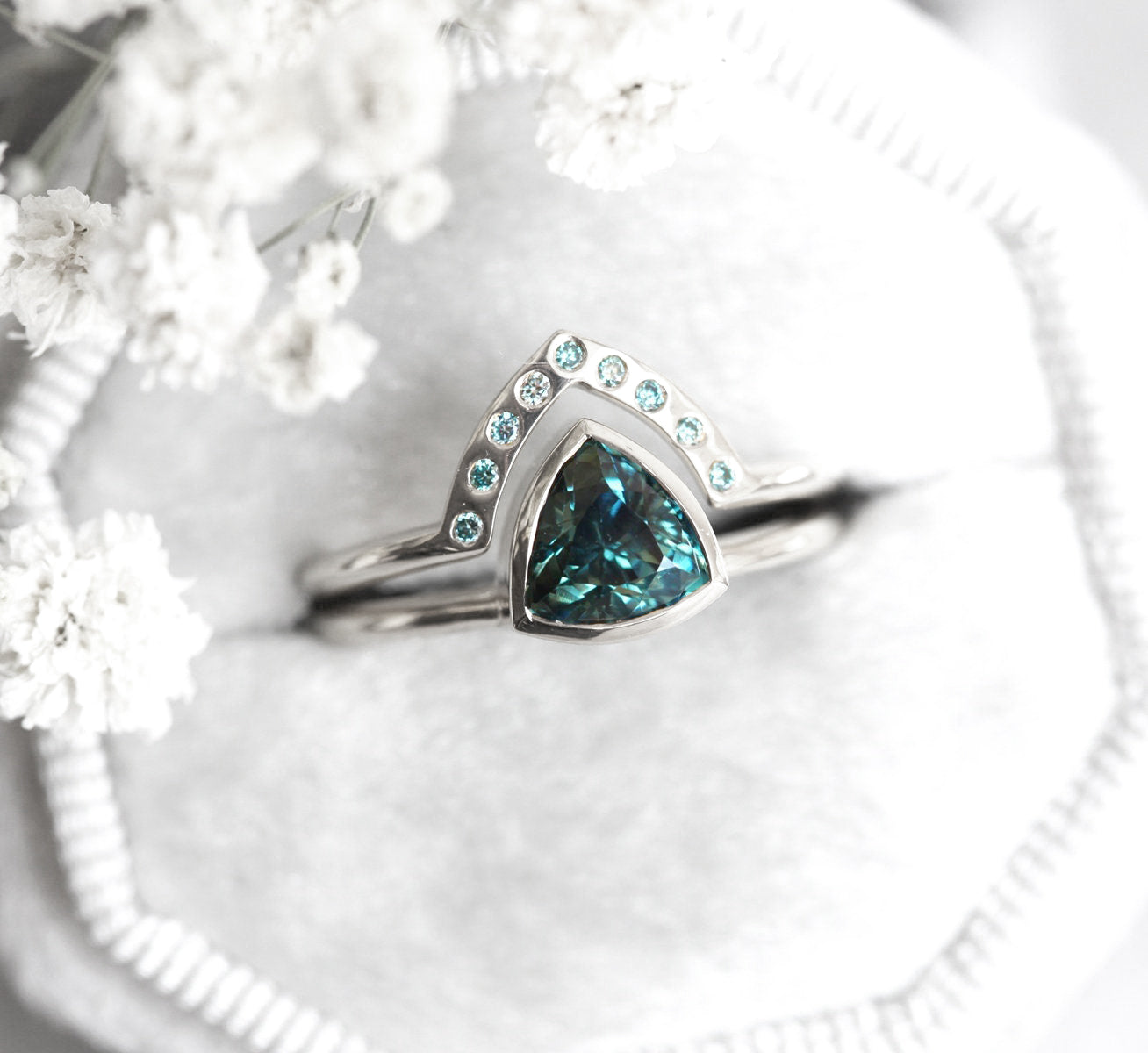 Trillion-cut teal sapphire engagement ring with blue diamond band