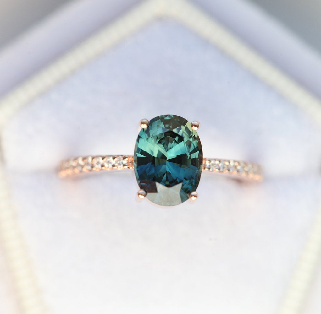 Oval-shaped teal sapphire eternity ring with diamonds
