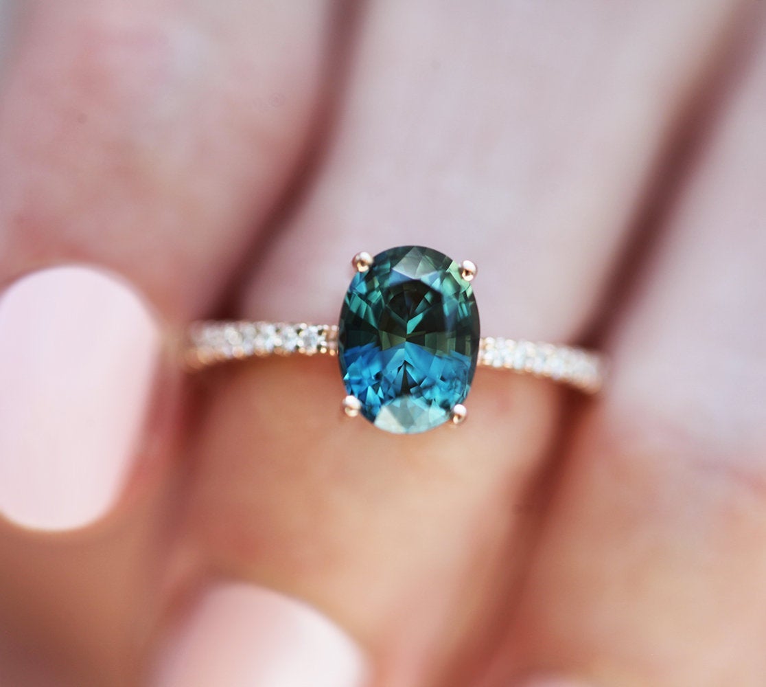 Oval-shaped teal sapphire eternity ring with diamonds