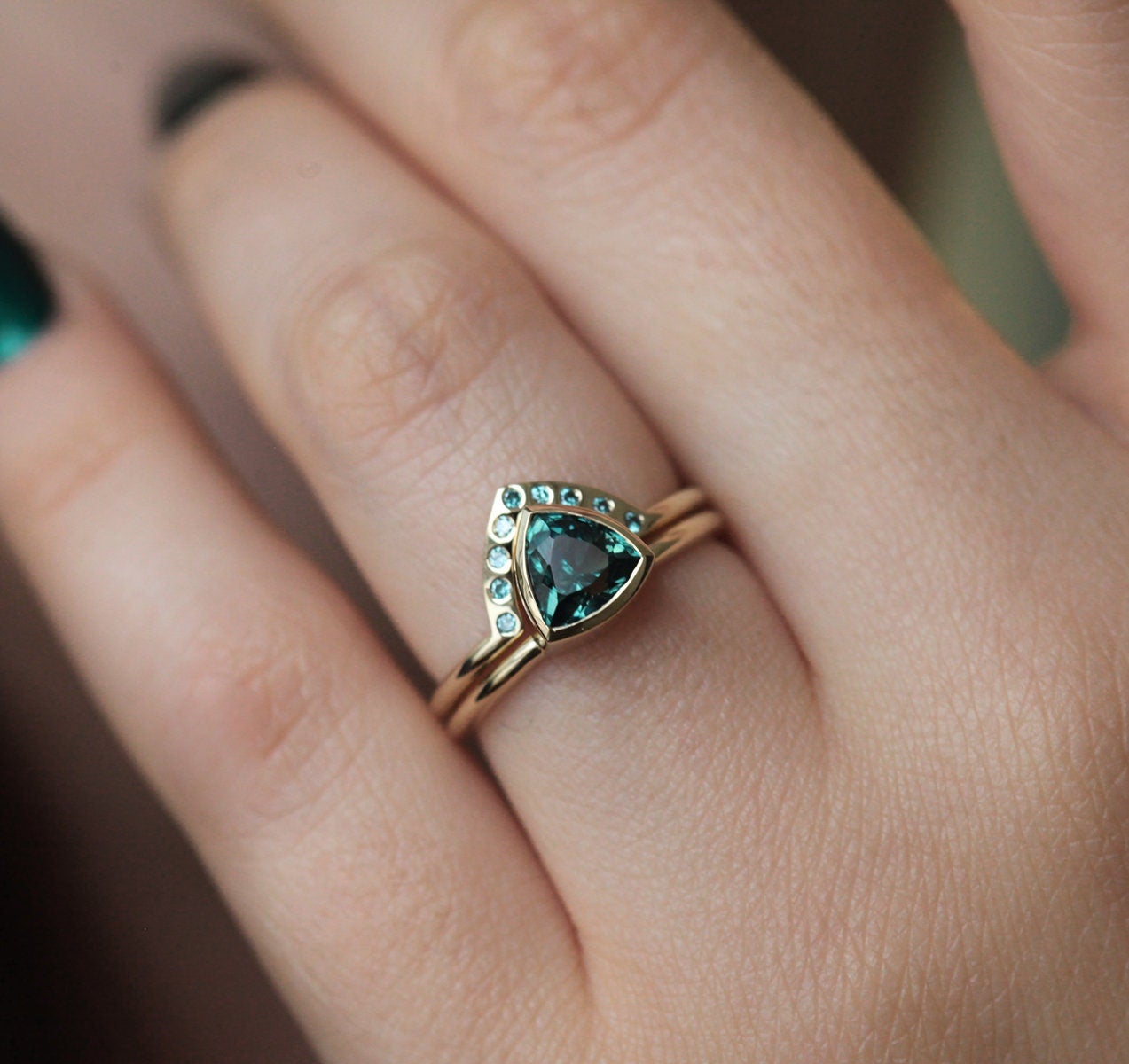 Trillion-cut teal sapphire engagement ring with blue diamond band