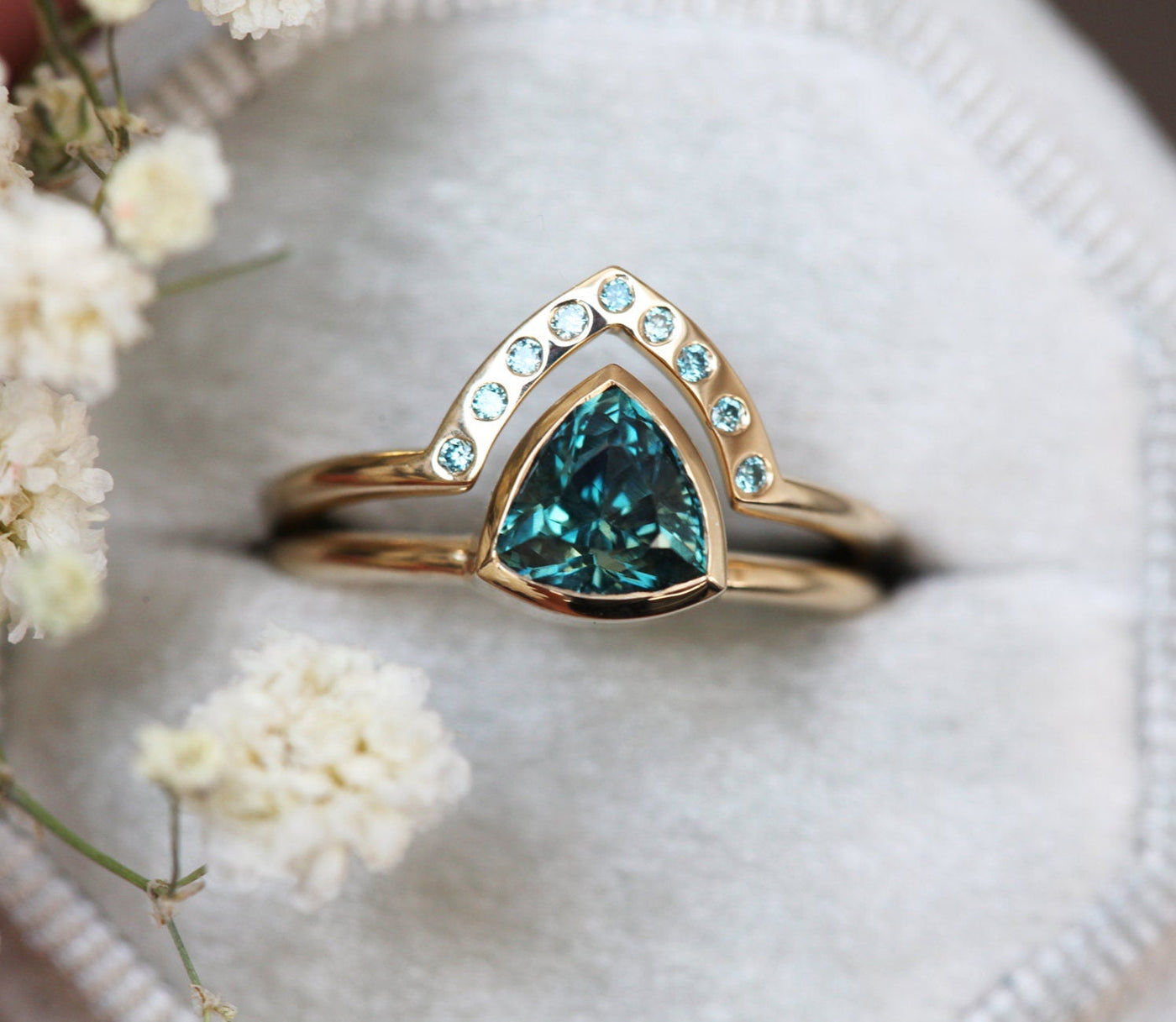 Trillion-cut teal sapphire engagement ring with blue diamond band