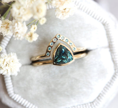 Trillion-cut teal sapphire engagement ring with blue diamond band