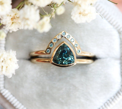 Trillion-cut teal sapphire engagement ring with blue diamond band