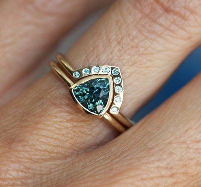 Trillion-cut teal sapphire engagement ring with blue diamond band