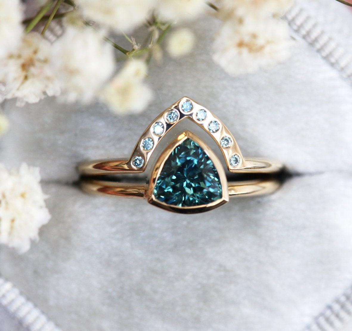 Trillion-cut teal sapphire engagement ring with blue diamond band