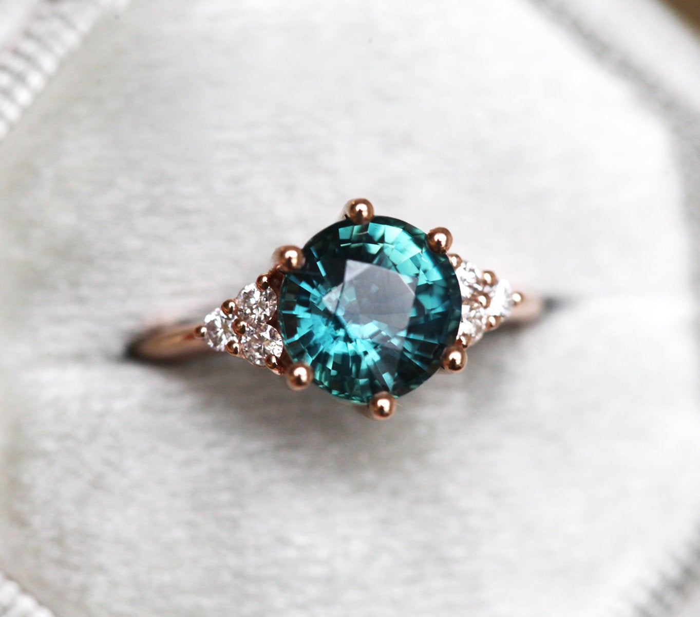 Round teal sapphire ring with white side diamonds