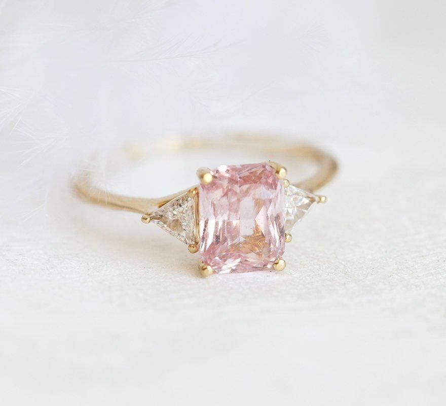 Radiant peach pink sapphire ring with white side diamonds