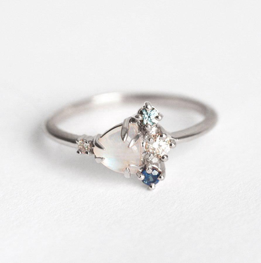 Trillion-cut white moonstone cluster ring with diamond and sapphire gemstones