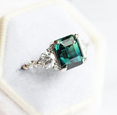 Radiant-cut teal sapphire cluster ring with white diamonds
