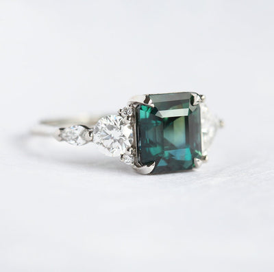 Radiant-cut teal sapphire cluster ring with white diamonds