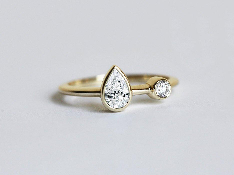 Pear-shaped white diamond engagement ring with round side diamond