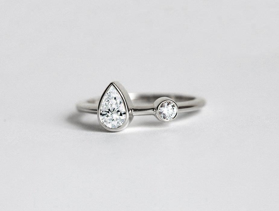 Pear-shaped white diamond engagement ring with round side diamond in platinum
