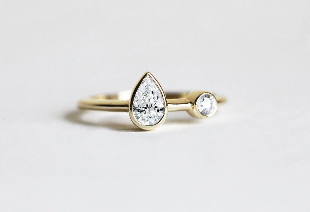 Pear-shaped white diamond engagement ring with round side diamond