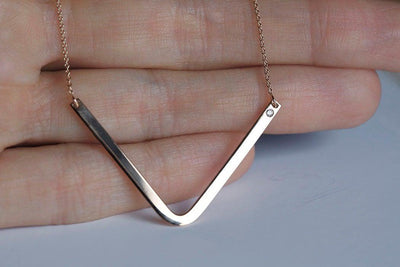 V-shaped curved gold bar chain necklace with round white diamond gem