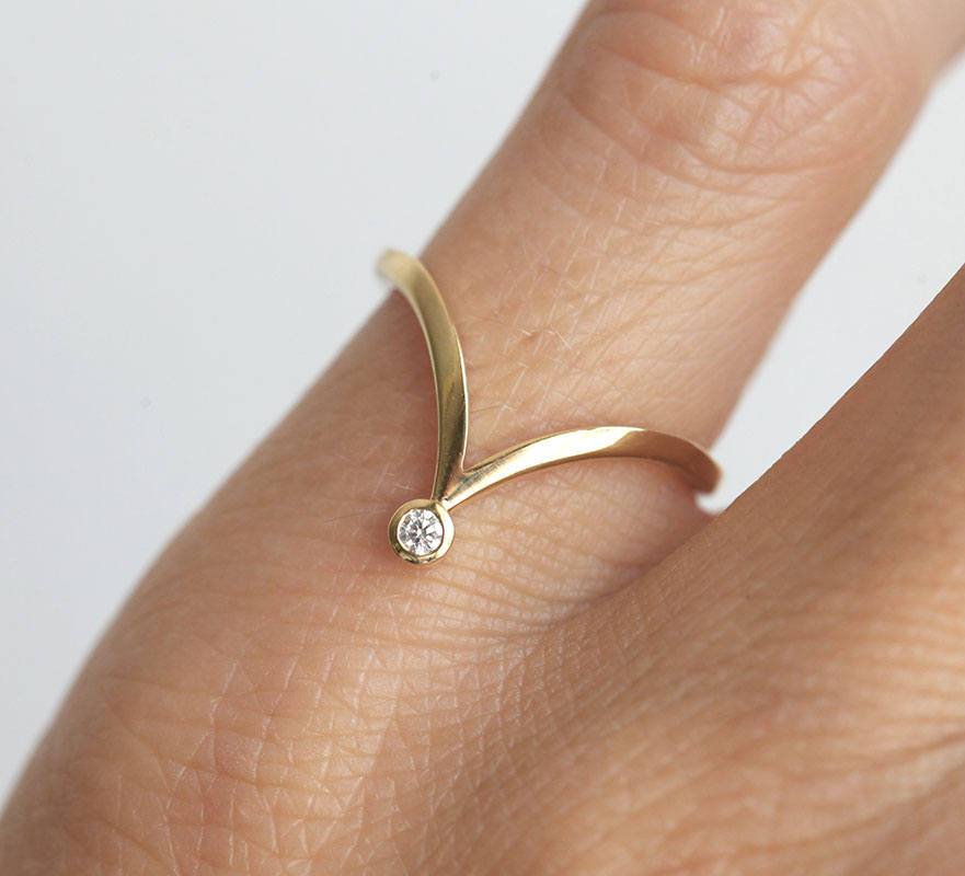V-shaped curved gold ring with nested pear-shaped white diamond
