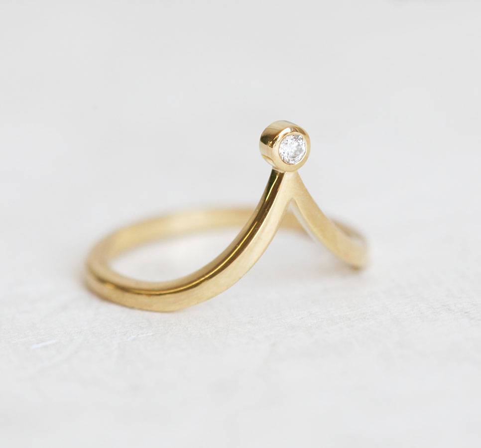 V-shaped curved gold ring with nested pear-shaped white diamond
