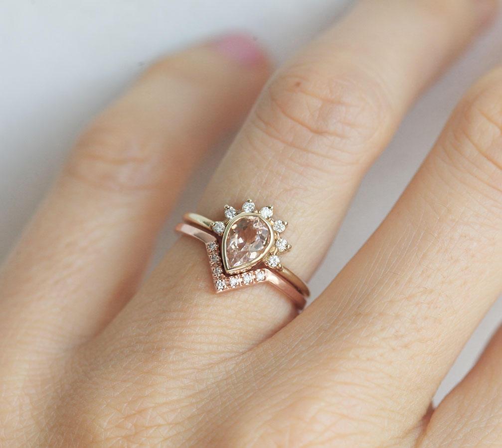 Nested round white diamond ring and pear-shaped peach pink sapphire ring with diamond halo