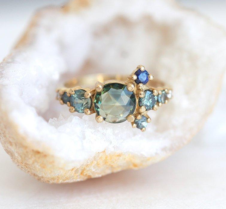 Round teal sapphire cluster ring with diamond and sapphire gemstones